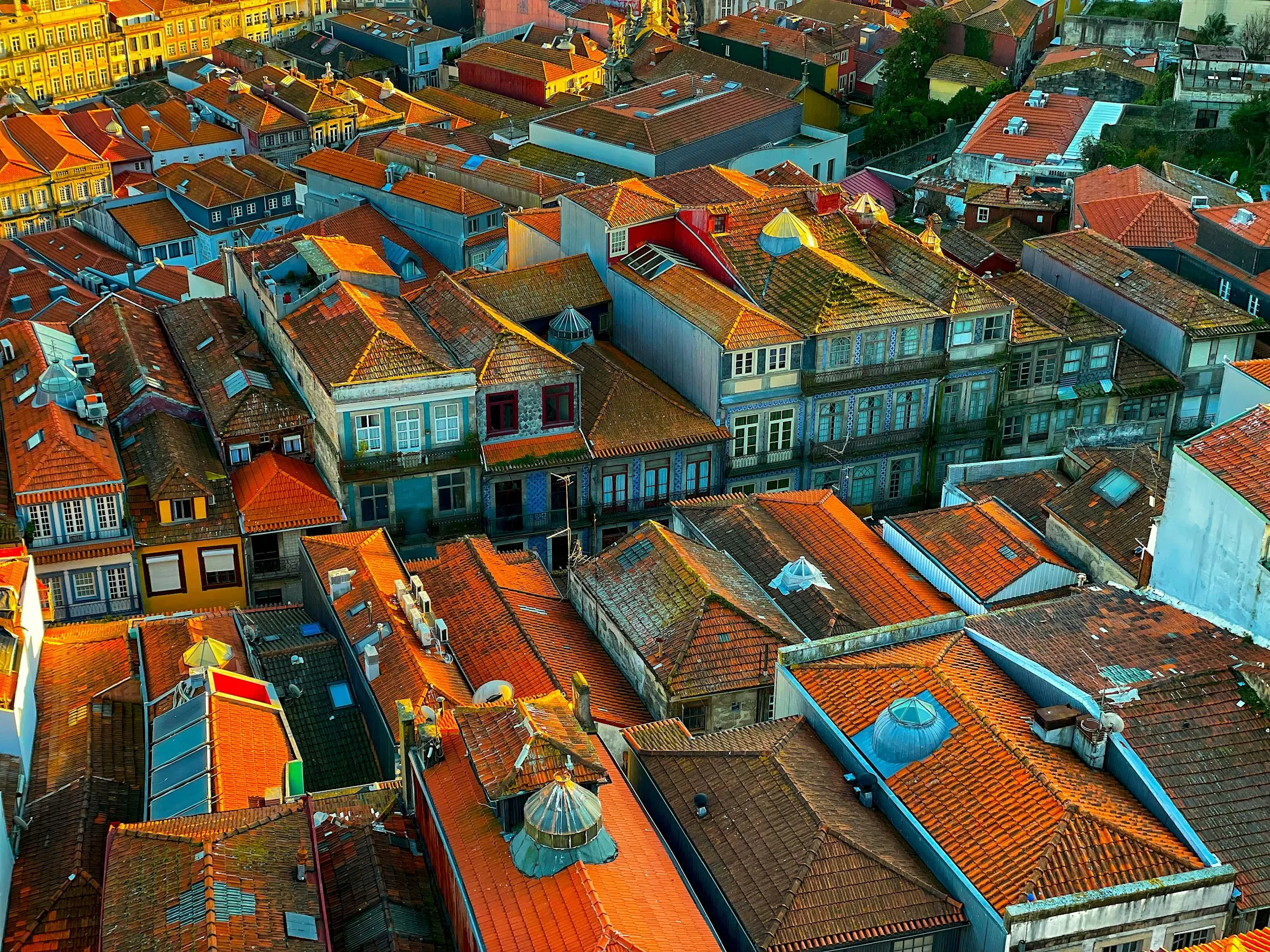 Aerial view of a European old town's red-tiled rooftops glowing in golden-hour light